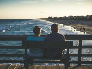 man and woman sitting on bench in front of beach by James Hose Jr courtesy of Unsplash.