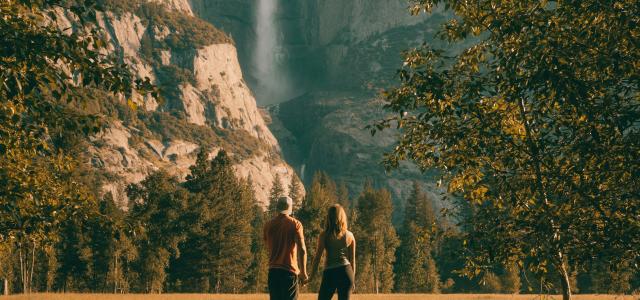 couple standing on tree trunk looking at field and forest by Jared Rice courtesy of Unsplash.